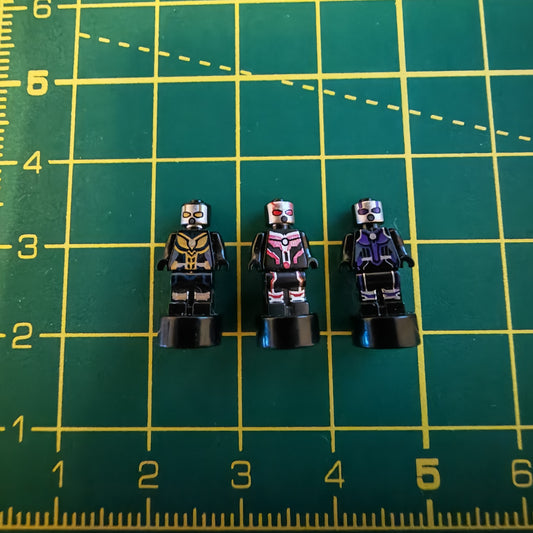 Three small figurines on a green grid with measurements